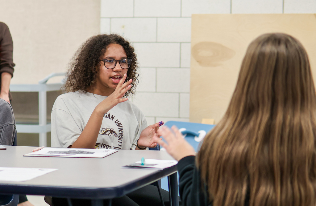 a girl speaking sitting a table