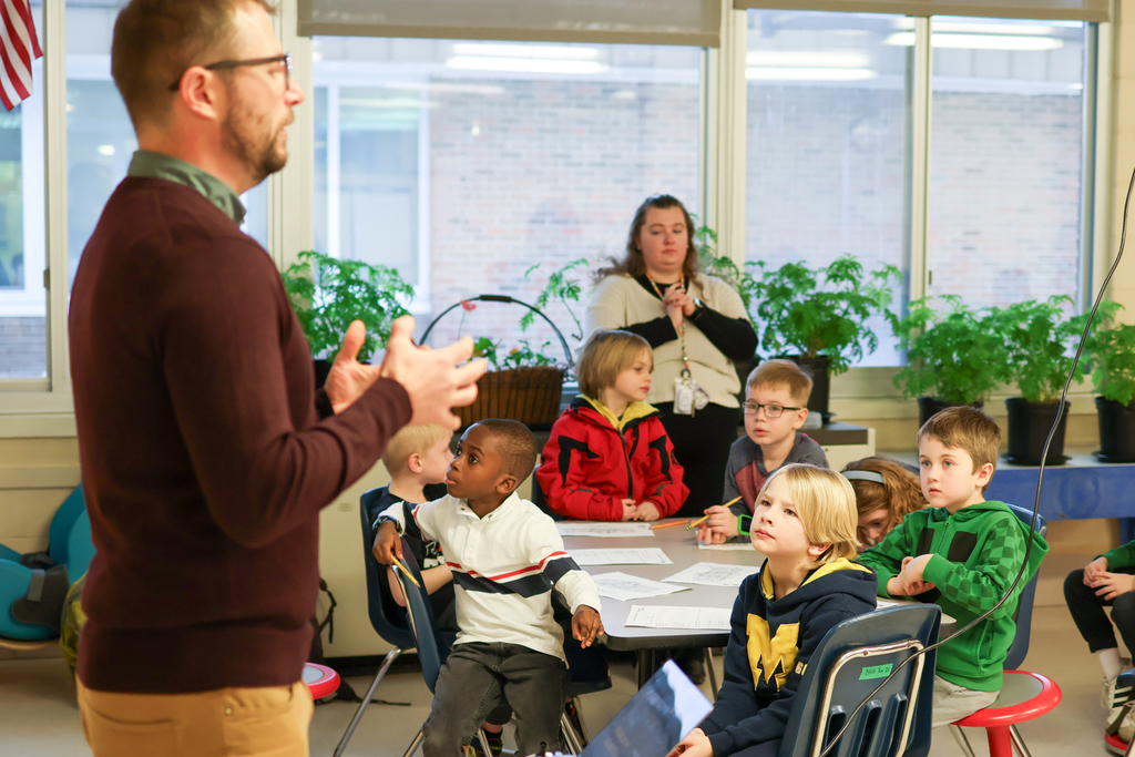 students listen to a man speaking in a classroom