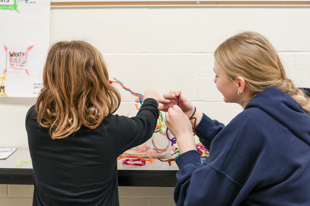 two girls playing with toys at a desk in a school hallway