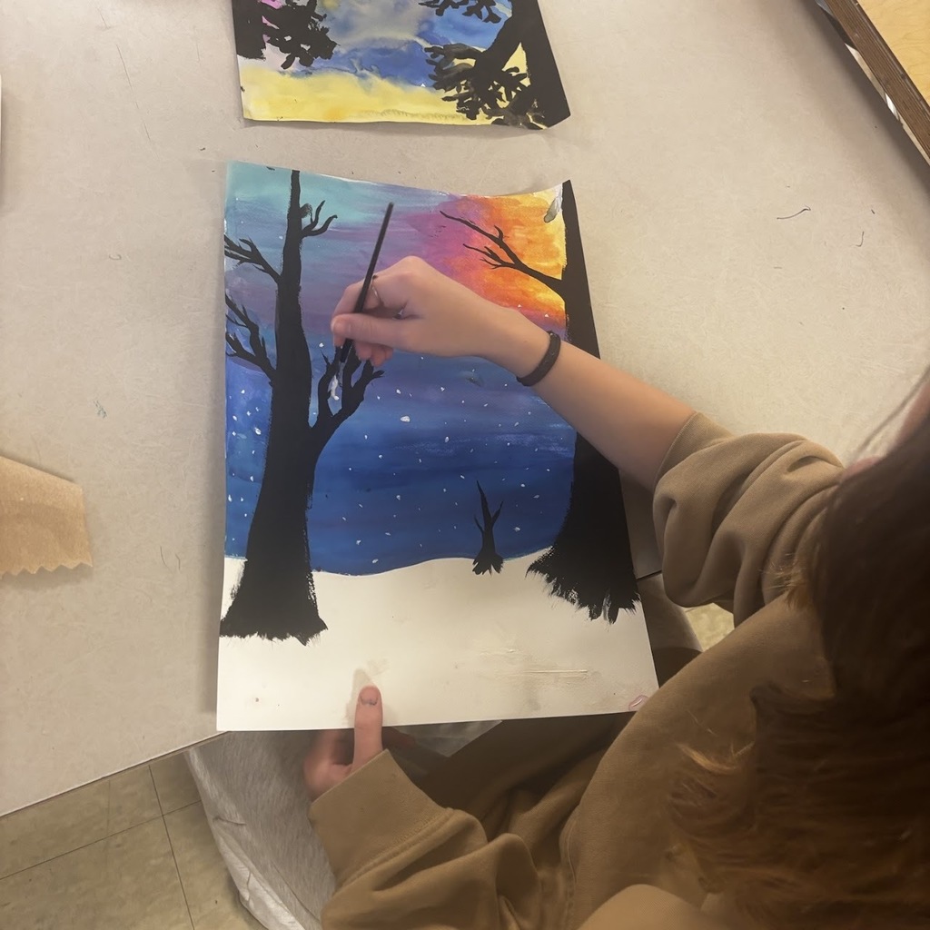 students painting landscape scenes at a desk