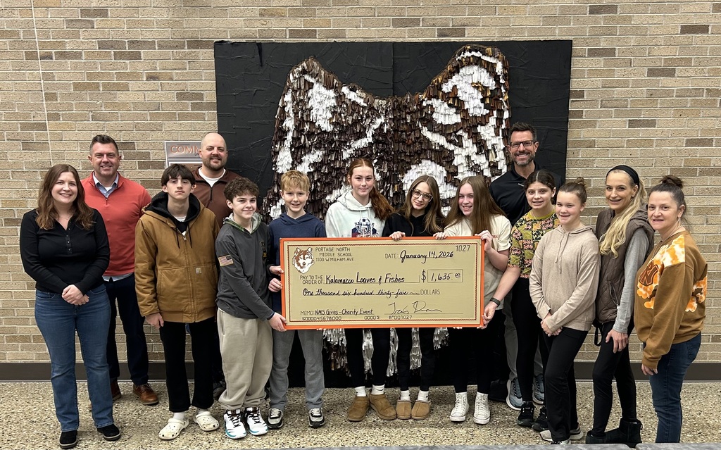 a group of students and staff pose together for a photo with a giant check