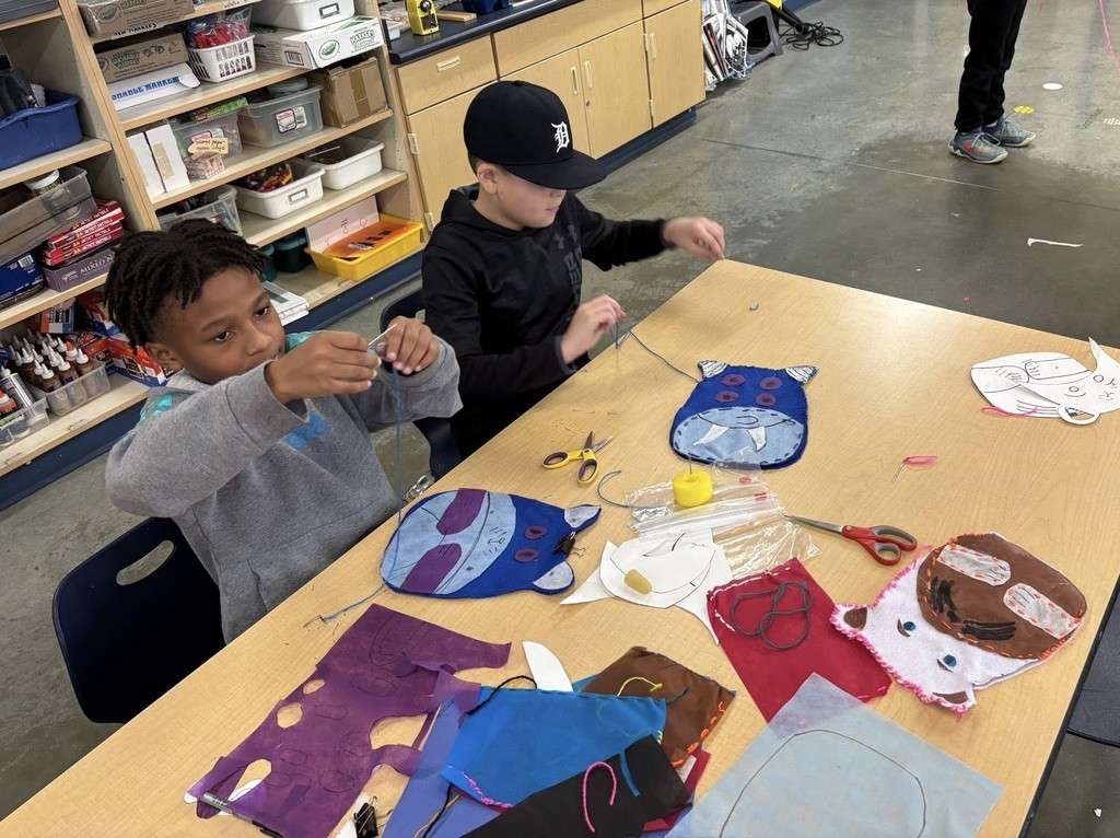 two boys sewing stuffed animals in a classroom