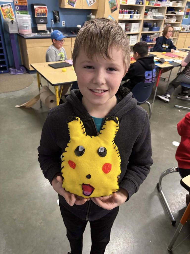 a boy holding a sewed stuffed animal smiling for a photo