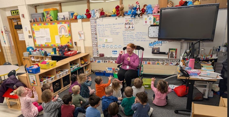 A music teacher leading a group in a song.