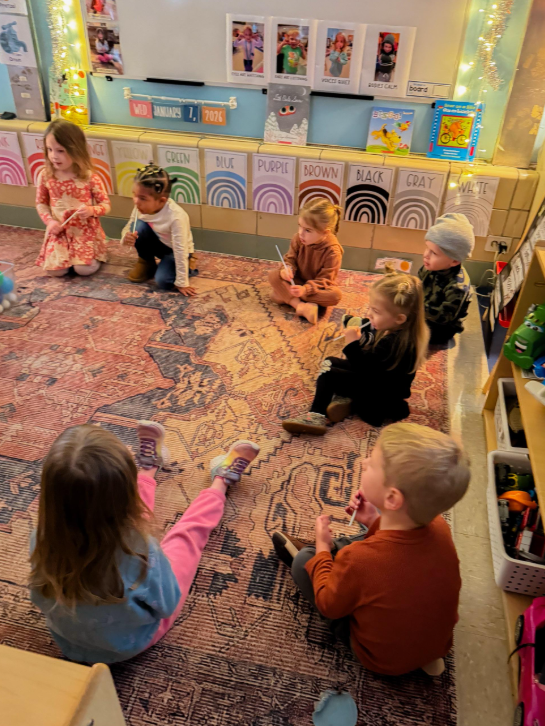 Students sitting at a carpet together.
