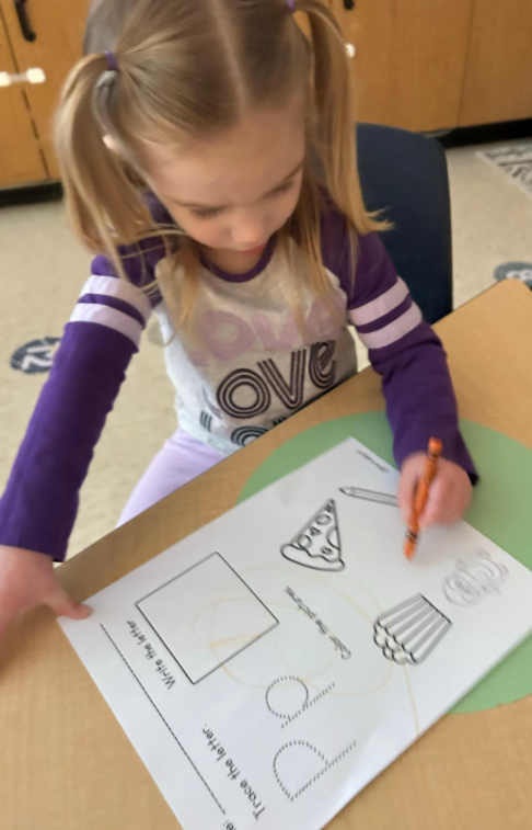 A little girl writting on a worksheet.