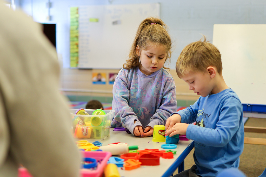 two students playing with play do in a classroom