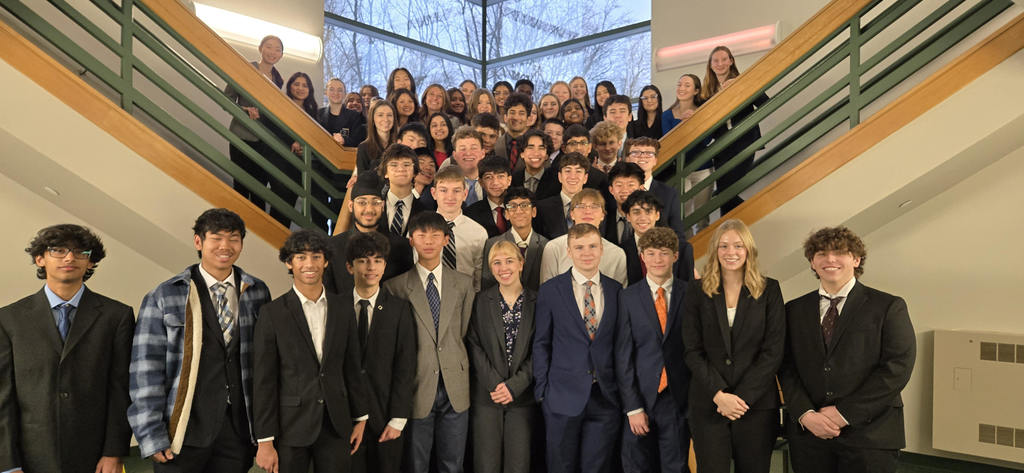 a large group of students pose for a photo inside a stairwell