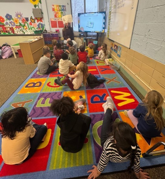 Student learning a speech lesson together on the carpet.