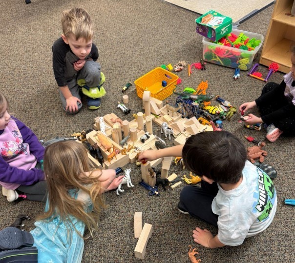 Two boys and a girl building blocks together.