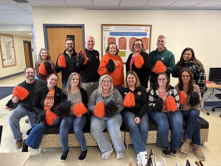 a group of people posing for a photo holding orange Pom poms 
