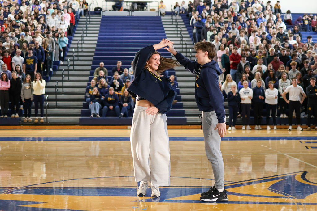 a boy and girl dance in the middle of a high school gym