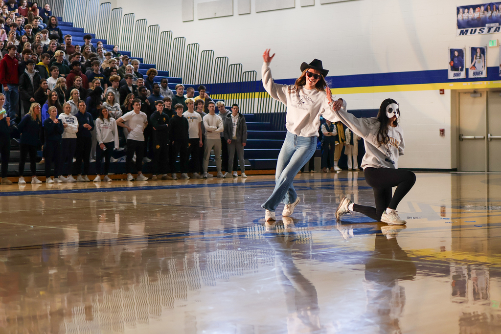 two girls perform a dance in the middle of a high school gym
