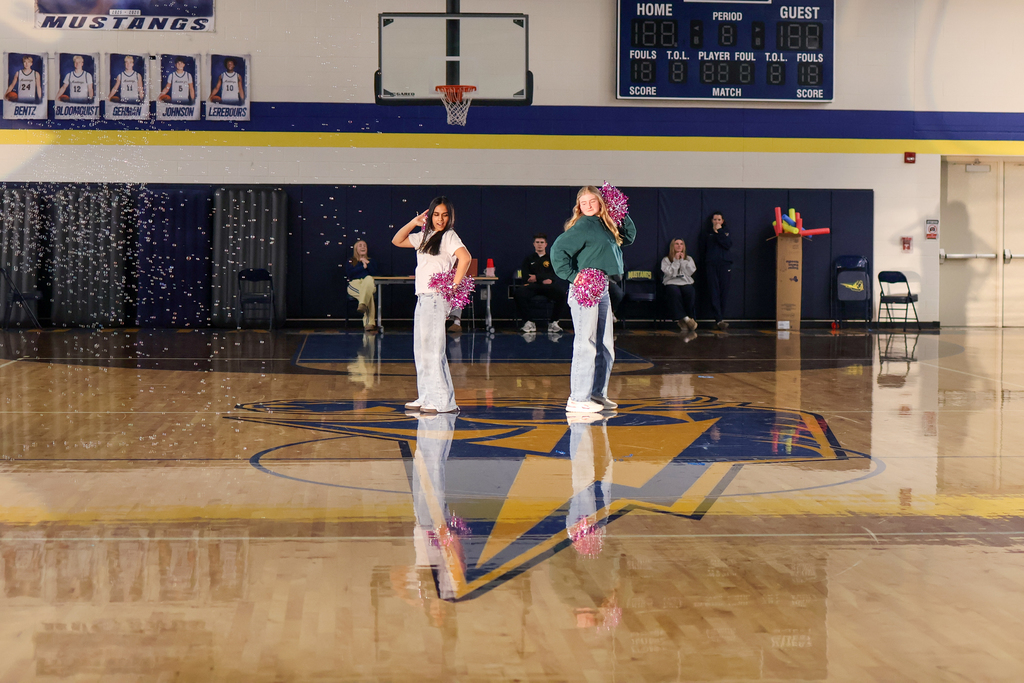 two girls perform a dance in the middle of a high school gym
