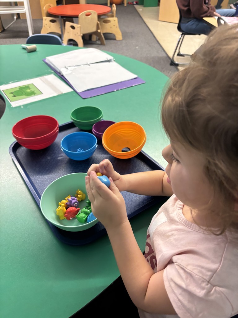 A female student sorting space items and shapes into various bowls.