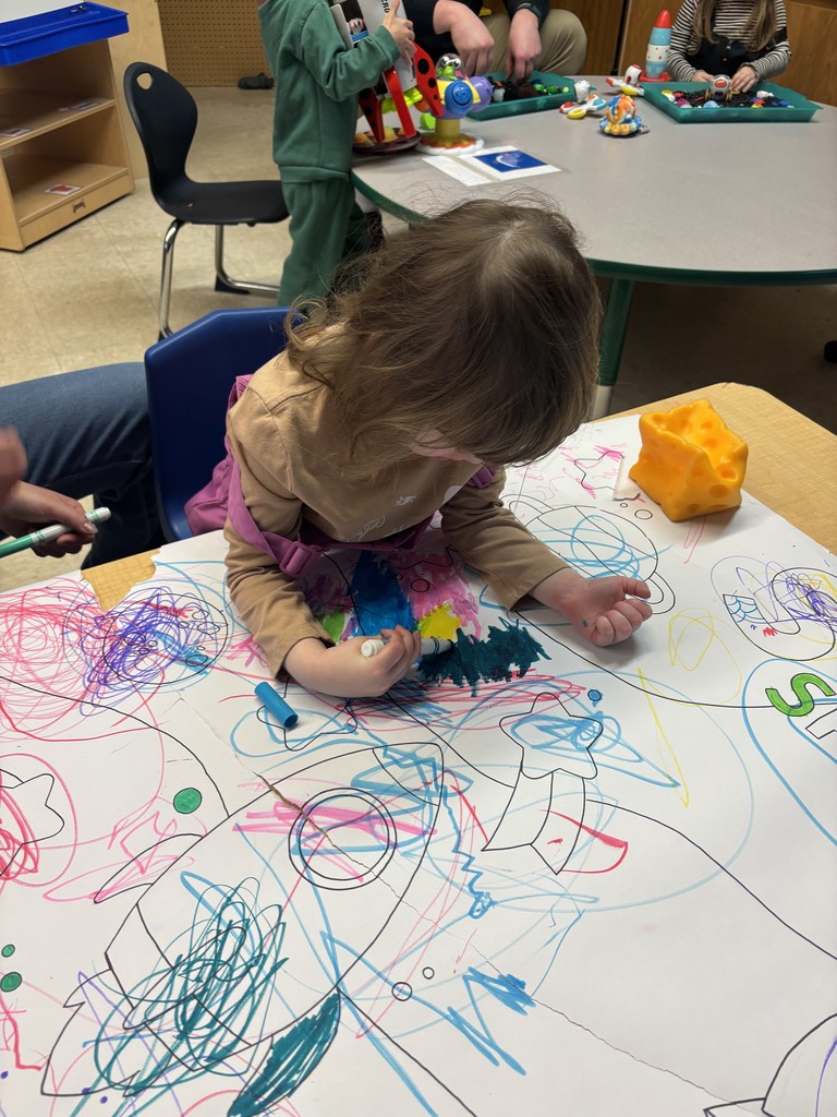 A female student coloring on a giant piece of paper and using lots of different colors.
