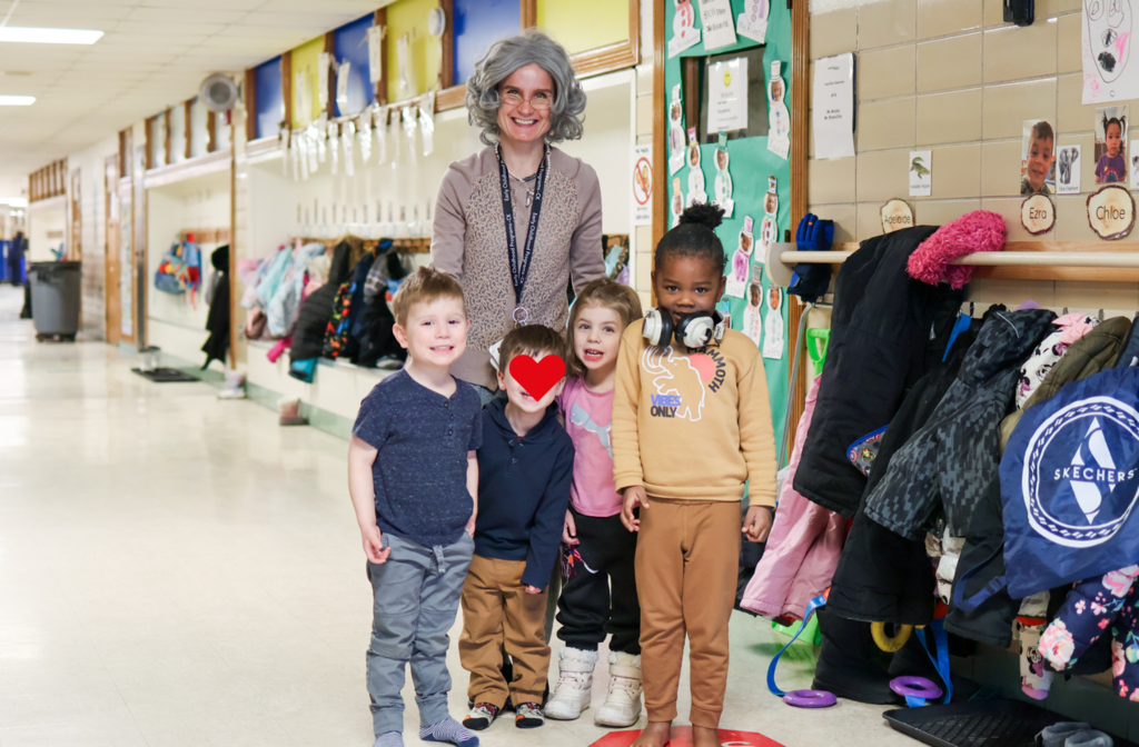 students and a teacher dressed as an old lady posing for a photo in a hallway