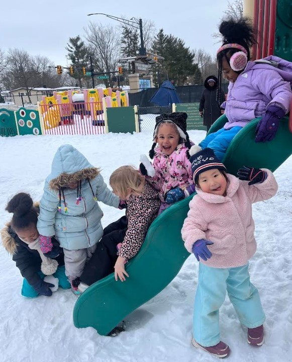 Preschool students on the slide outside on the playground.