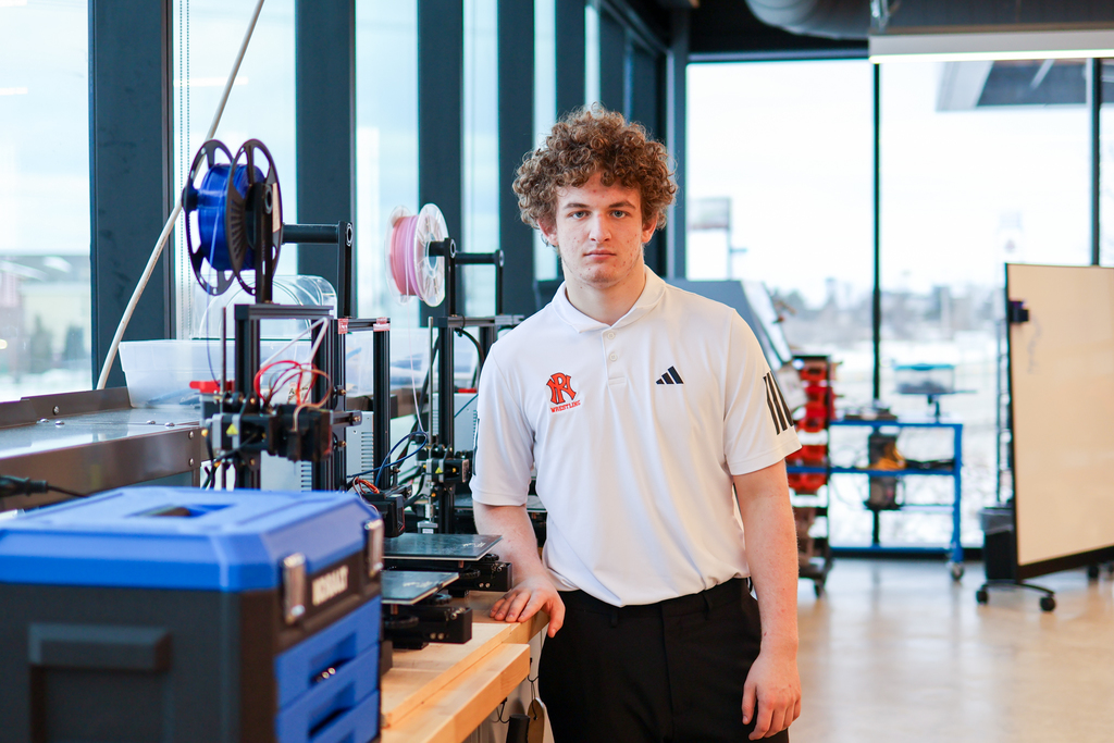 a boy poses for a photo in a mechatronics lab