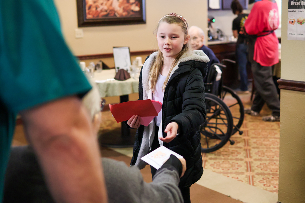 a girl hands someone a valentine's card