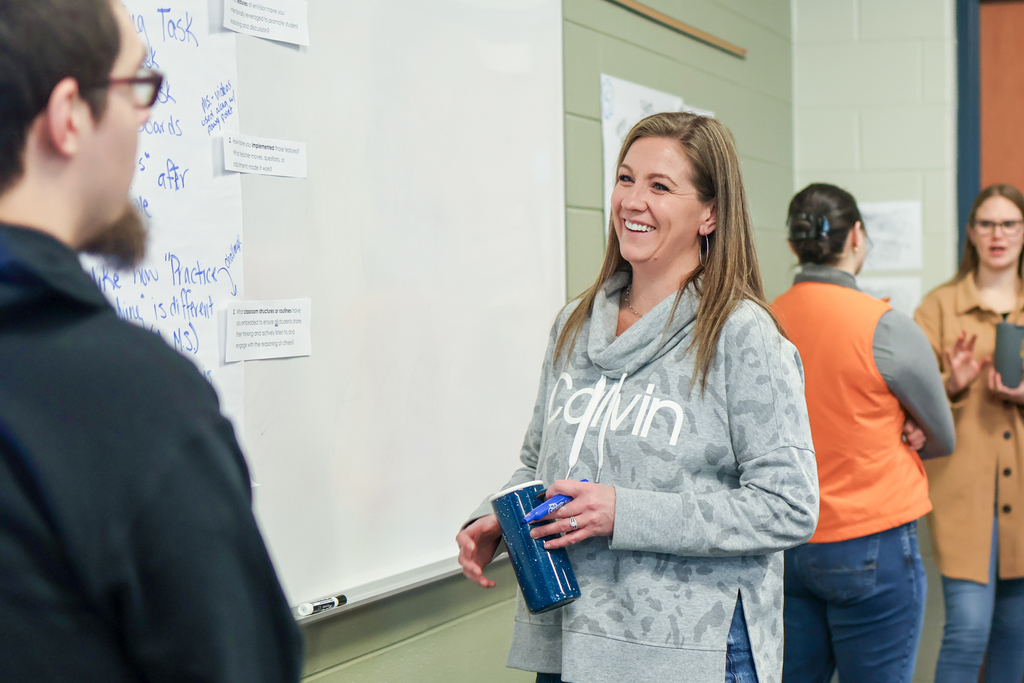 a woman smiling standing near a white board in a classroom