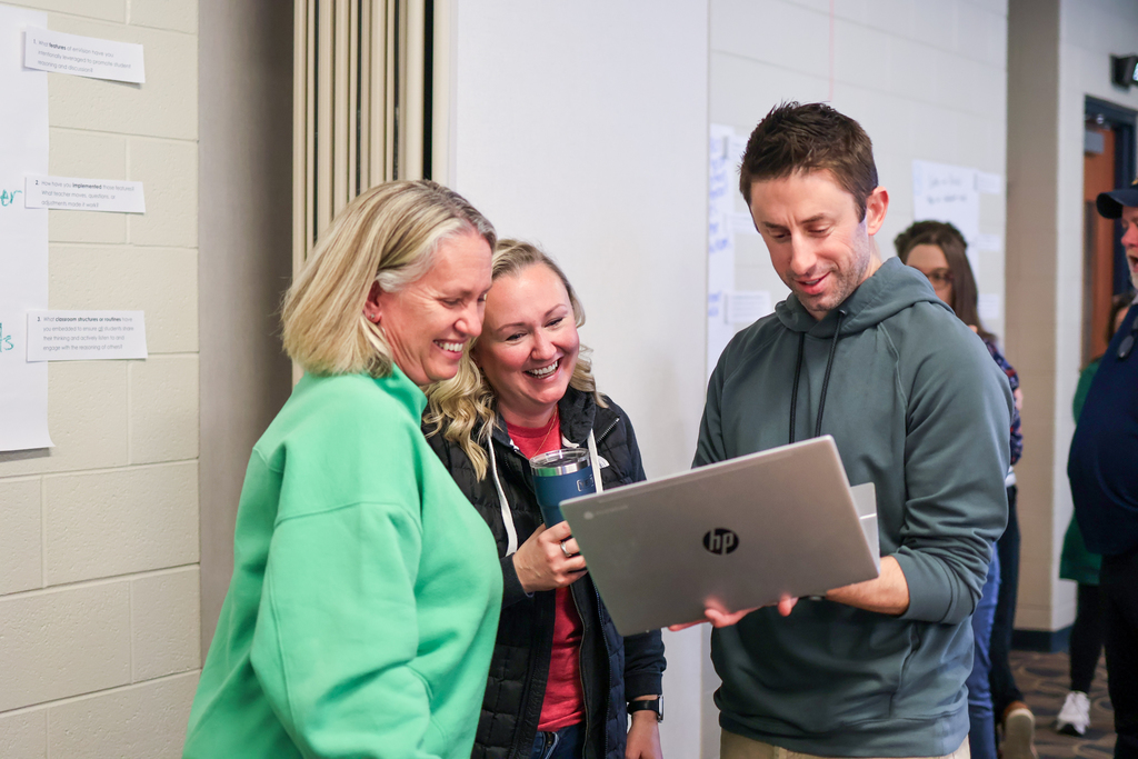 three people huddled together looking at a laptop