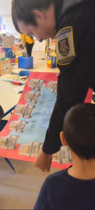 Student looking at a poster with Officer Burleson.