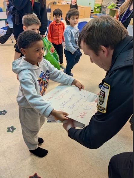A student handing a police officer a card.