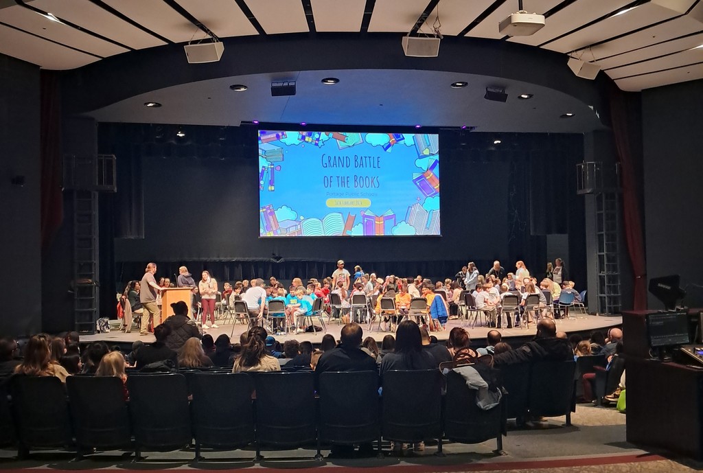 students sitting on a stage in an auditorium