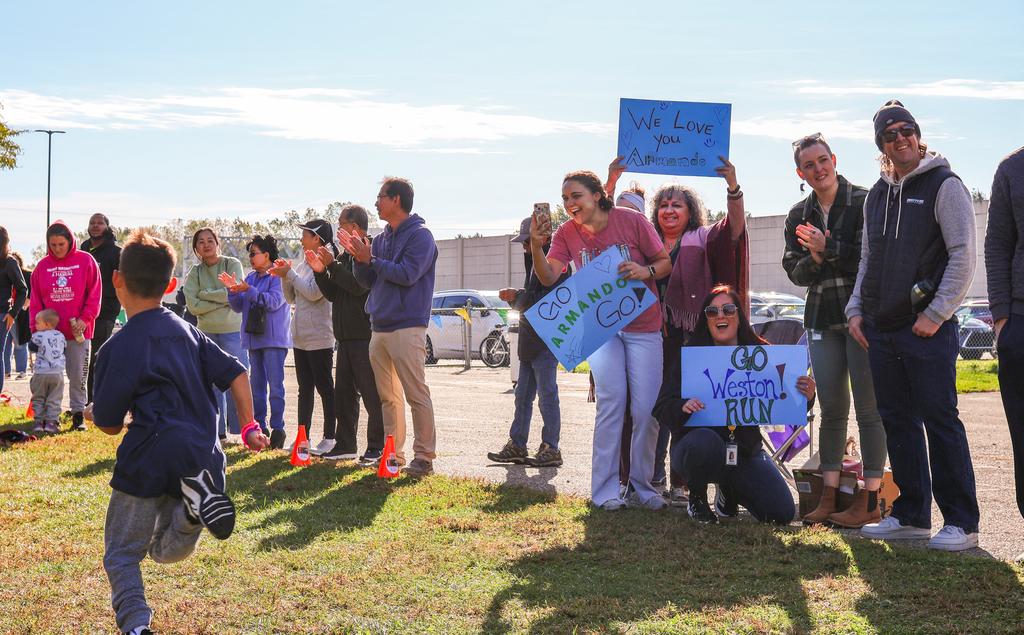 families cheer with signs outside an elementary school