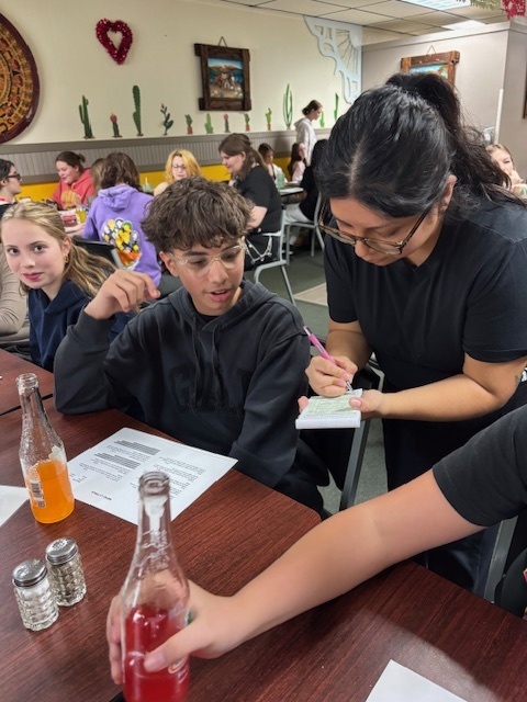 a student speaking to a waitress inside a restaurant