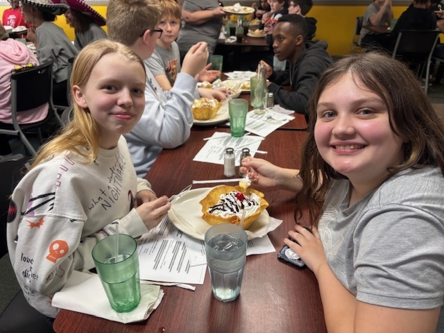 two students smile for a photo sitting at a restaurant 