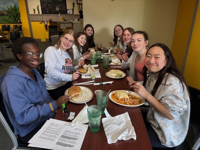 a group of students smile for a photo sitting at a restaurant table