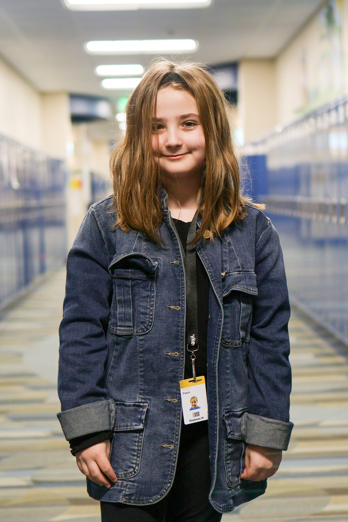 a girl standing in a school hallway posing for a photo