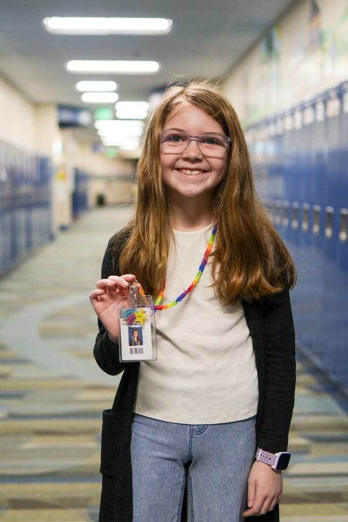 a little girl holding her badge smiles for the camera