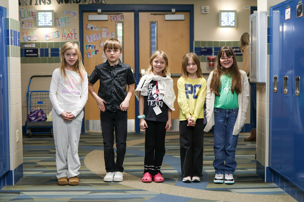 a group of kids standing in a school hallway pose for a photo