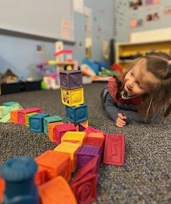 A girl making a tower on the floor.