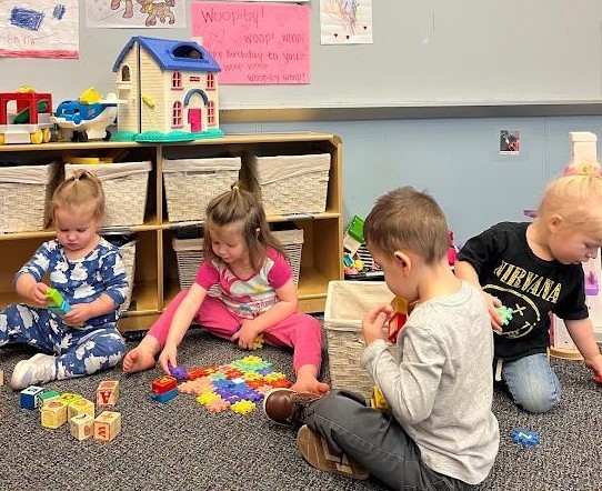 Four students sitting together working on a colorful puzzel.