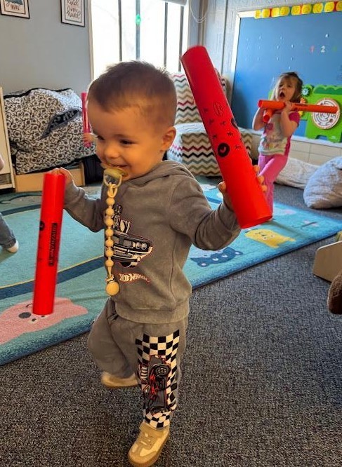 A little boy running with music sticks