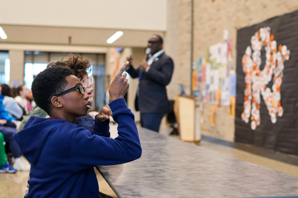 a student listens to a man speaking in a cafeteria