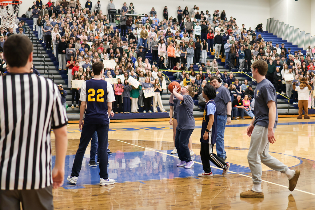 a girl shoots a basketball during a game in the school gym