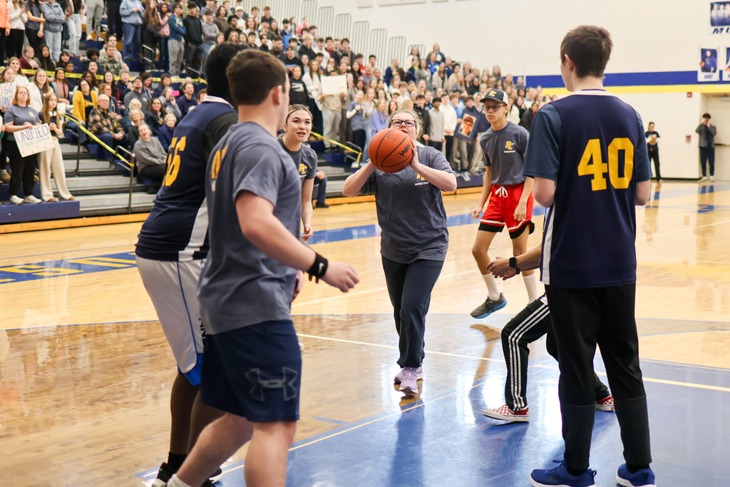 a girl shoots a basketball during a game in the school gym