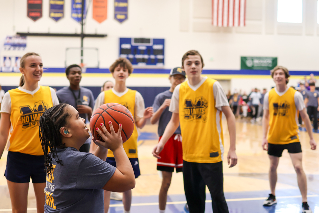 a girl shoots a basketball during a game in the school gym