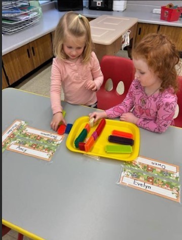 Two female students lining up long blocks at a table.
