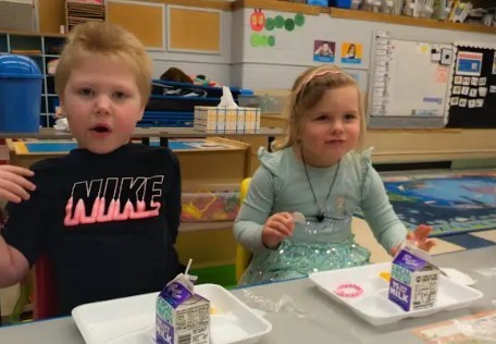 A boy and a girl eating lunch together at a table.