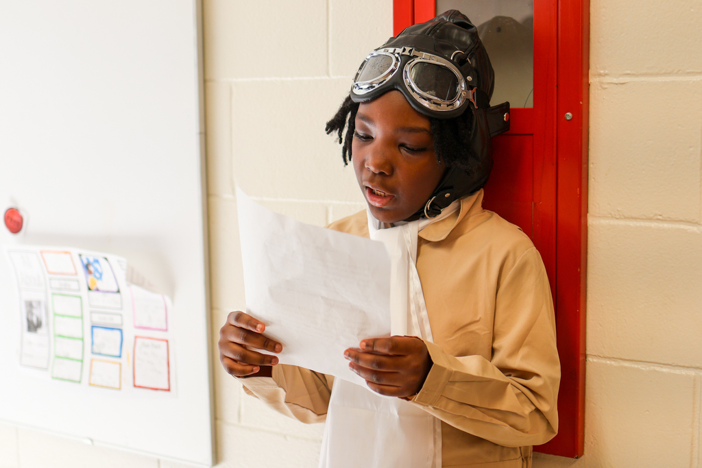 a student dressed like an airplane pilot reads from a paper