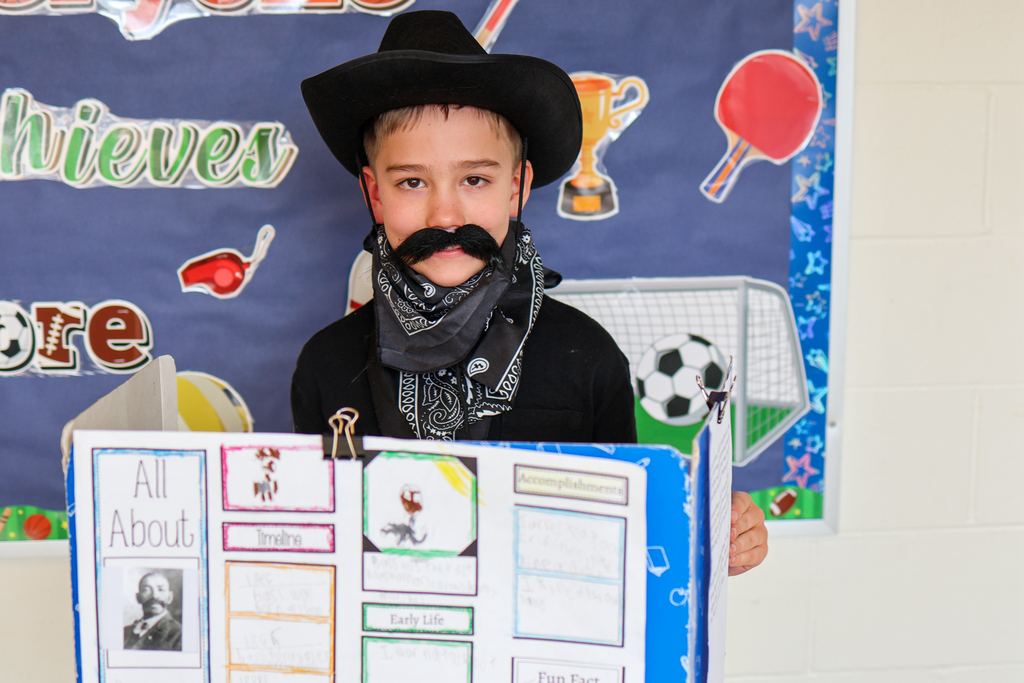 a boy wearing a cowboy hat and fake mustache poses for a photo