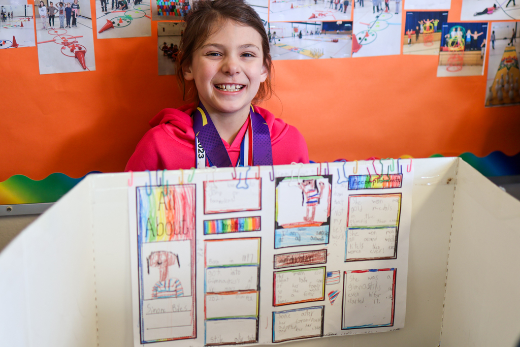 a girl smiles for a photo posing in front of her project