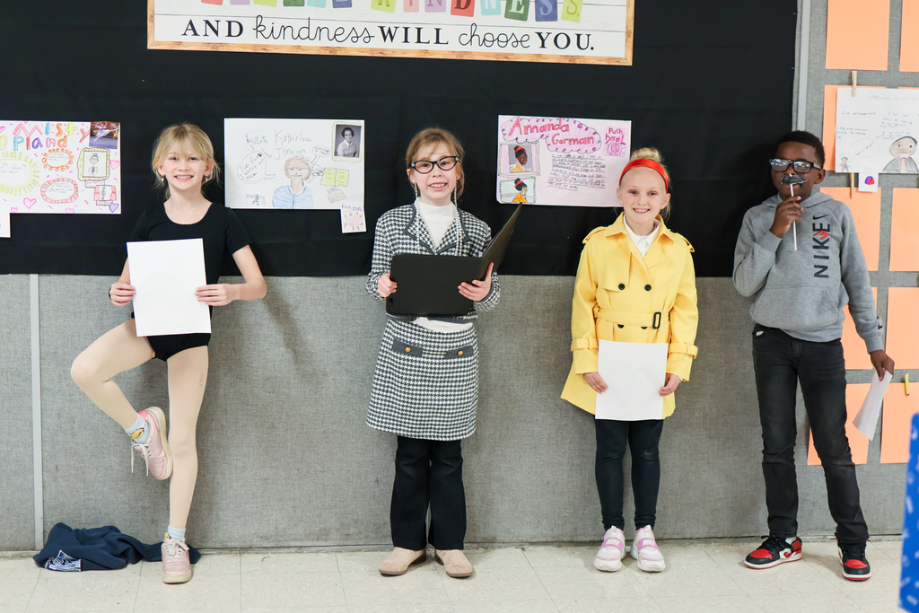 four students pose for a photo in front of their posterboards 