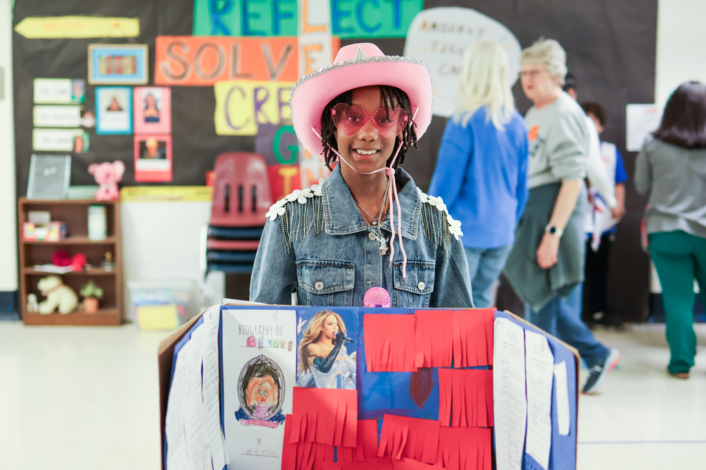 a little girl dressed up as Beyonce standing in front of a posterboard